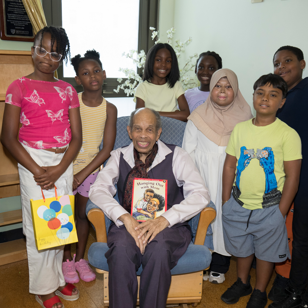 older man seated surrounded by children