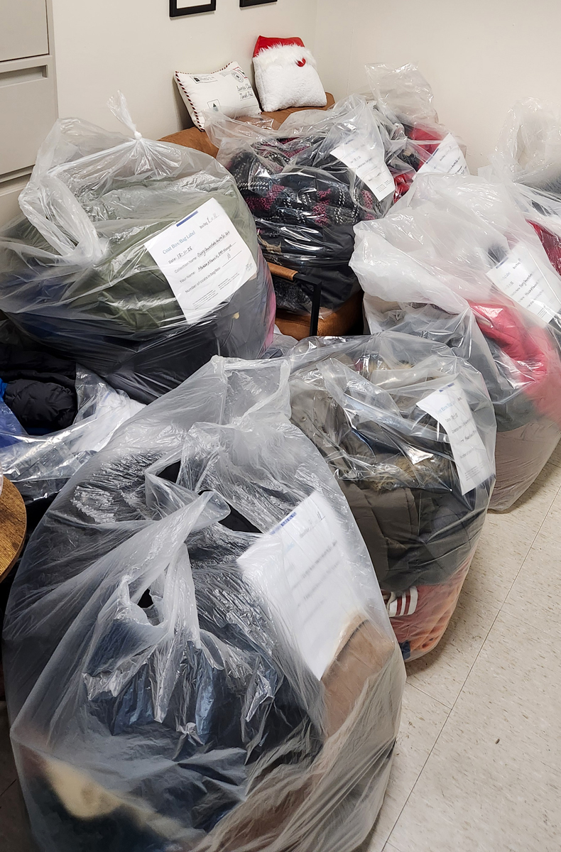 photo of large plastic bags filled with coat donations gathered on the floor