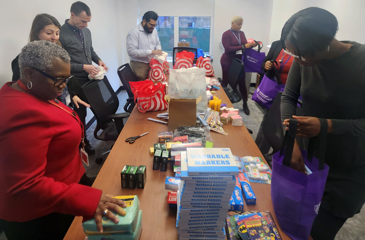 photo of 7 people standing by a table piled with items and bags for distribution