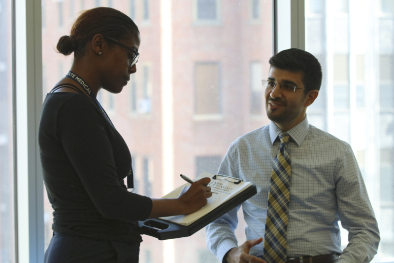 young lady taking notes talking to man