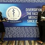 Sierrah Grigsby standing with another naval officer in front of event poster