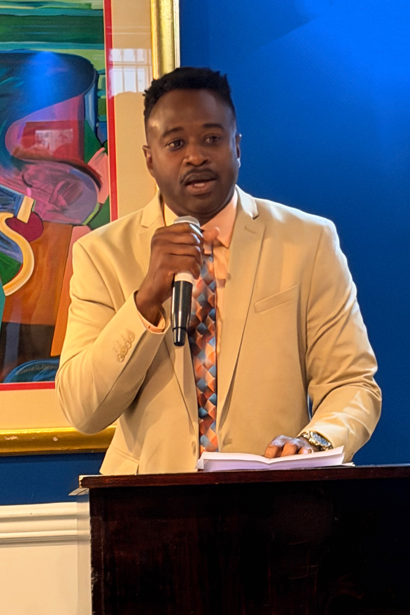 photo of Kijana Corbin standing at podium with a mic in his hand