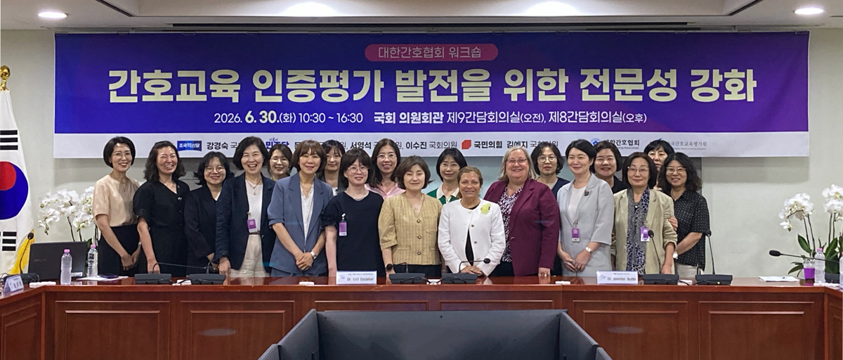 group photo women standing in a long row in front of a poster in Korean.