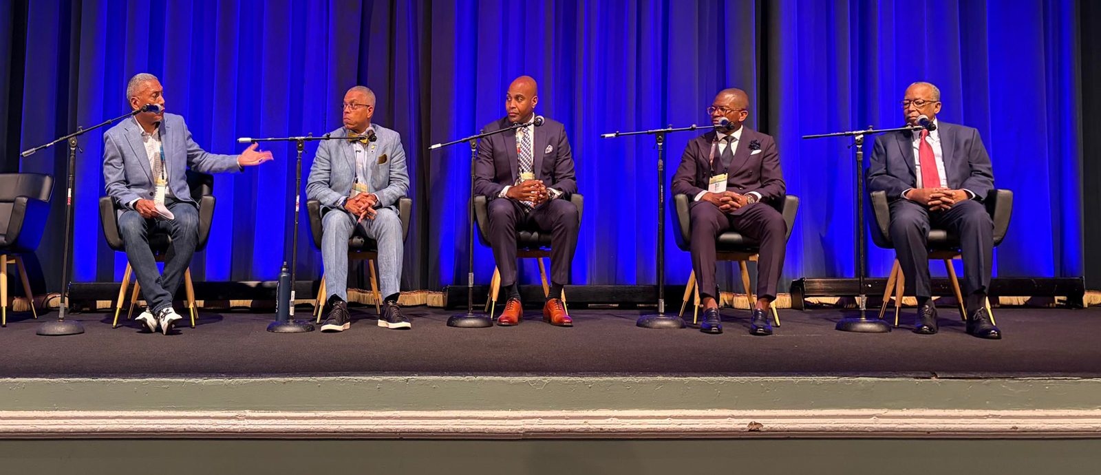 five men seated on stage